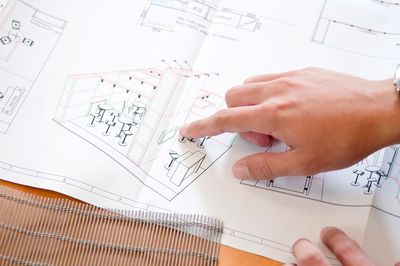 Der rechte Zeigefinger einer männlichen Hand zeigt auf eine skizzierte Büroplanung