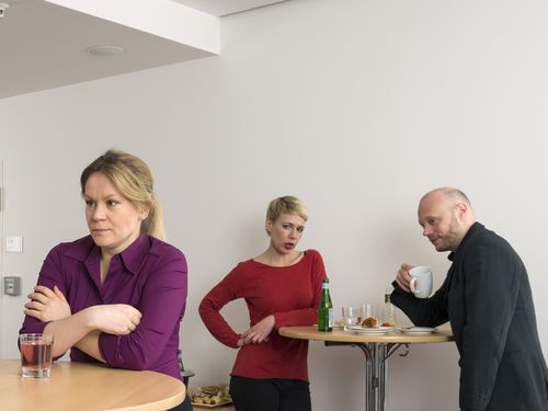 Eine Frau steht am Stehtisch mit einem Glas