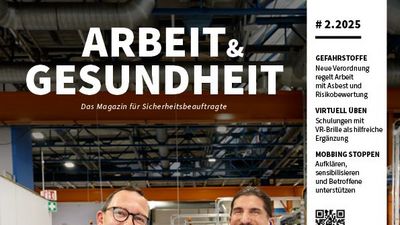 Zwei Männer stehen hinter einer Maschine und lachen in die Kamera