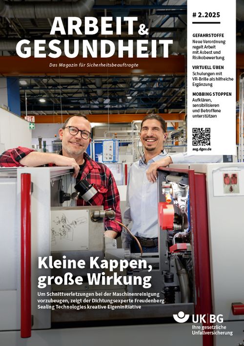 Zwei Männer stehen hinter einer Maschine und lachen in die Kamera