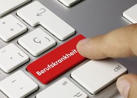 Auf einer roten Computertastatur steht das Wort Berufskrankheit