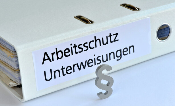 Ein weißer Ordner trägt die schwarze Aufschrift Arbeitsschutz, Unterweisungen
