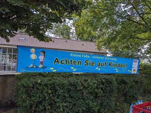 Ein blauer Banner mit der Aufschrift "Kleine Füße - sicherer Schulweg"