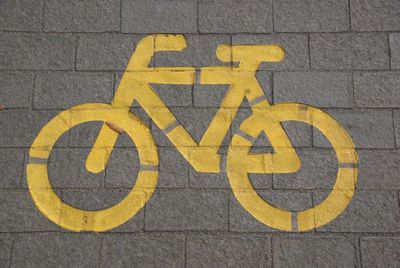 Gelbes Fahrradsymbol auf einem gepflasterten Weg