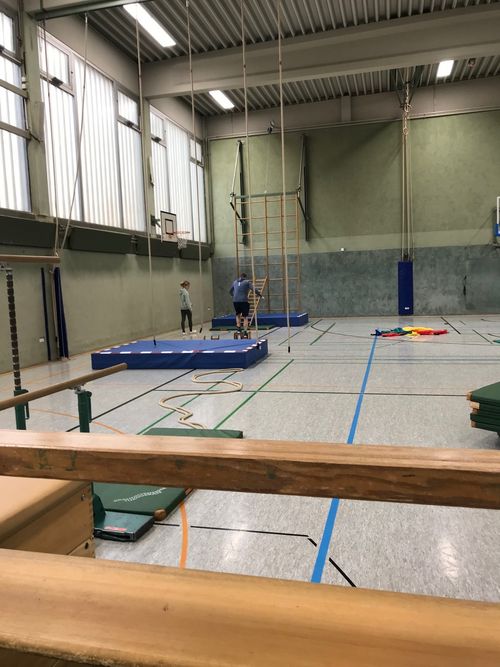 In einer Turnhalle sind mehrere Bänke und Turngeräte aufgebaut