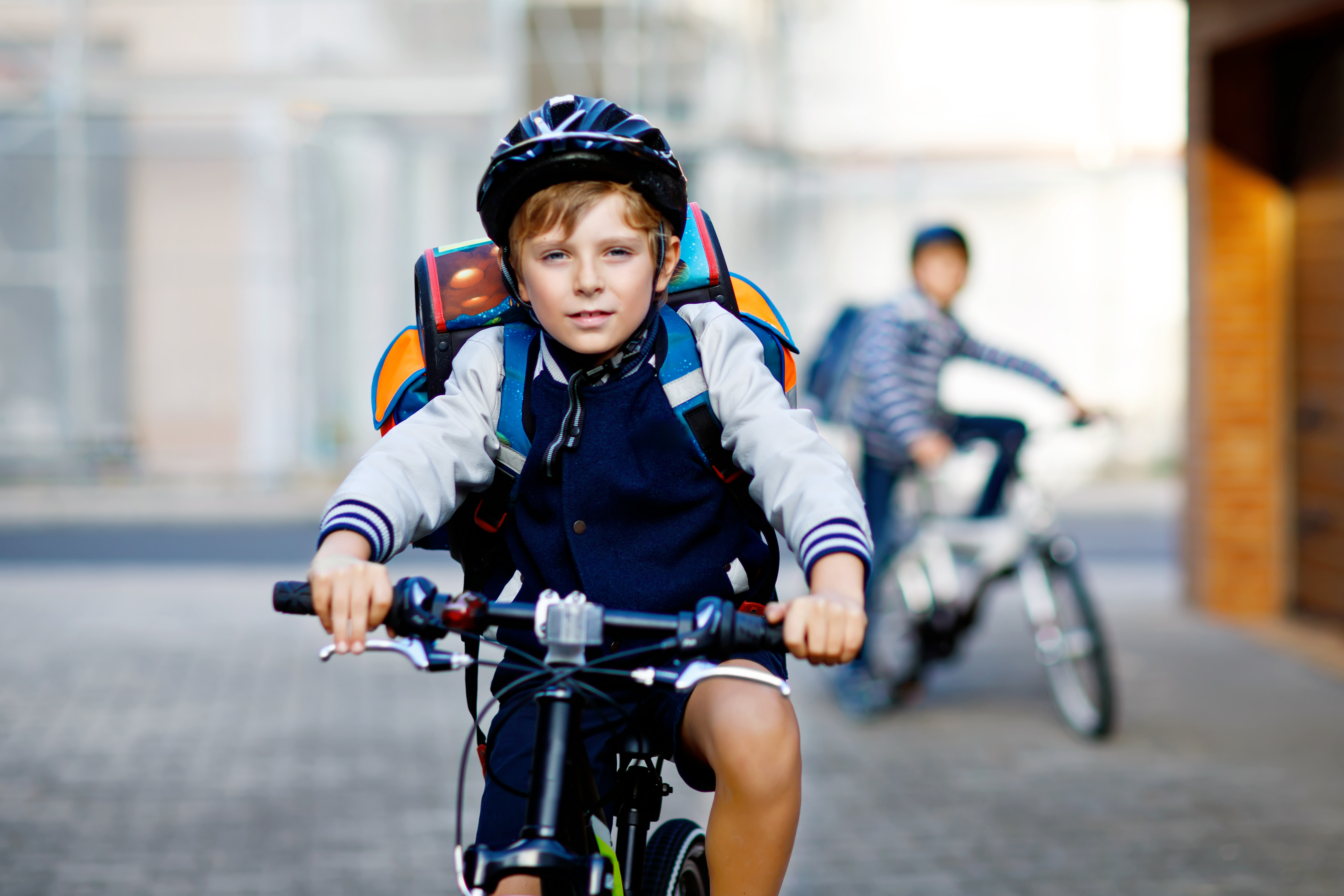 Ein Junge mit Helm und Ranzen auf dem Fahrrad