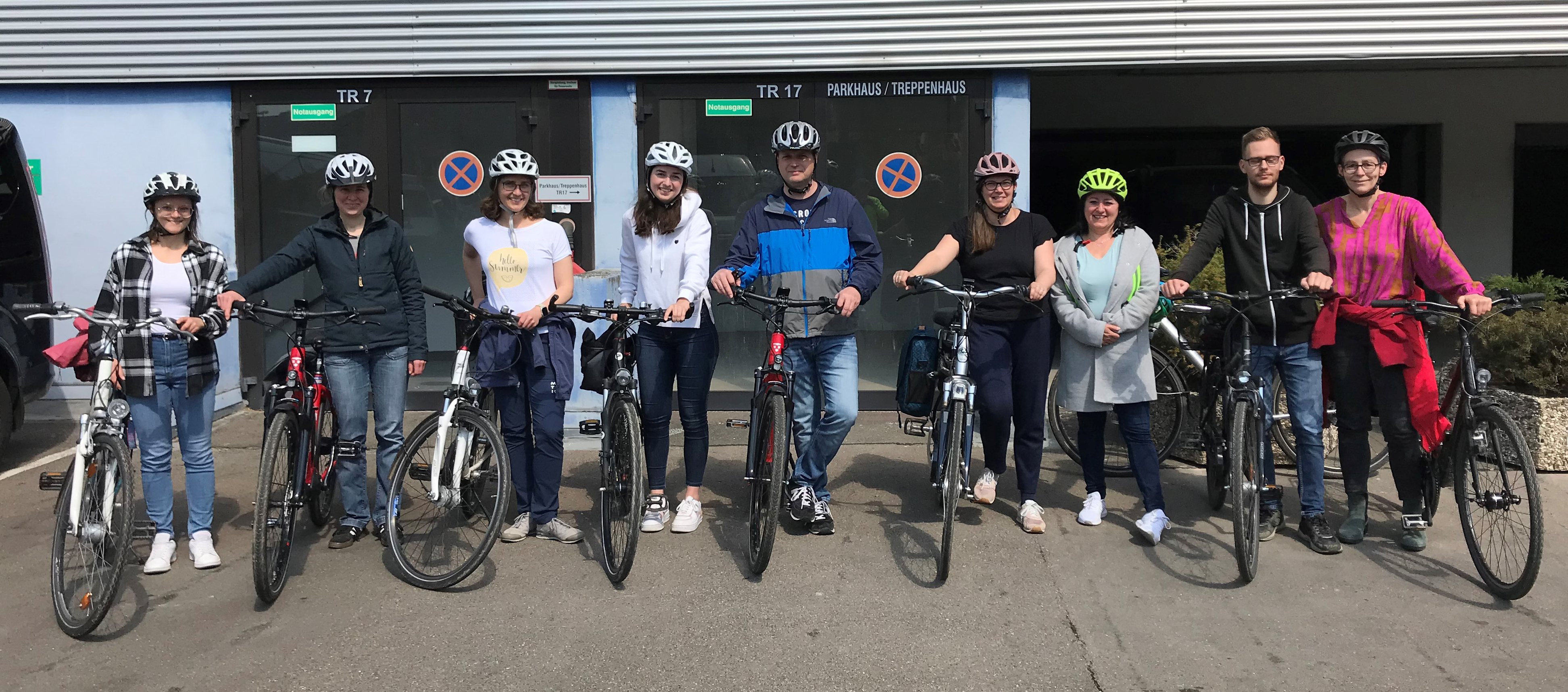 Teilnehmer des Fahrrad-Sicherheitstrainings stehen mit Fahrrädern und Fahrradhelmen vor einem Gebäude